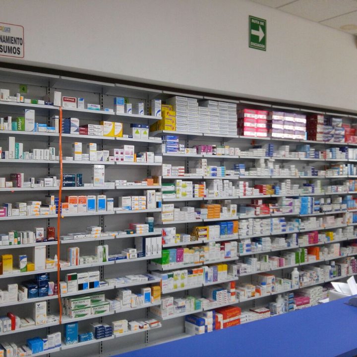 Anaquel de medicamentos ordenado por laboratorio detrás del mostrador