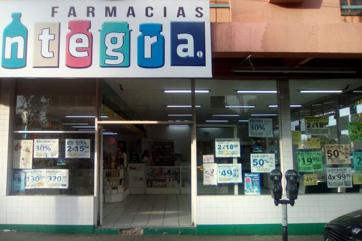 Fachada de una sucursal de Farmacias Integra con su letrero de frascos de colores