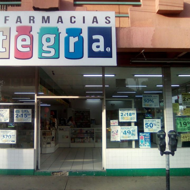 Fachada de una sucursal de Farmacias Integra con su letrero de frascos de colores